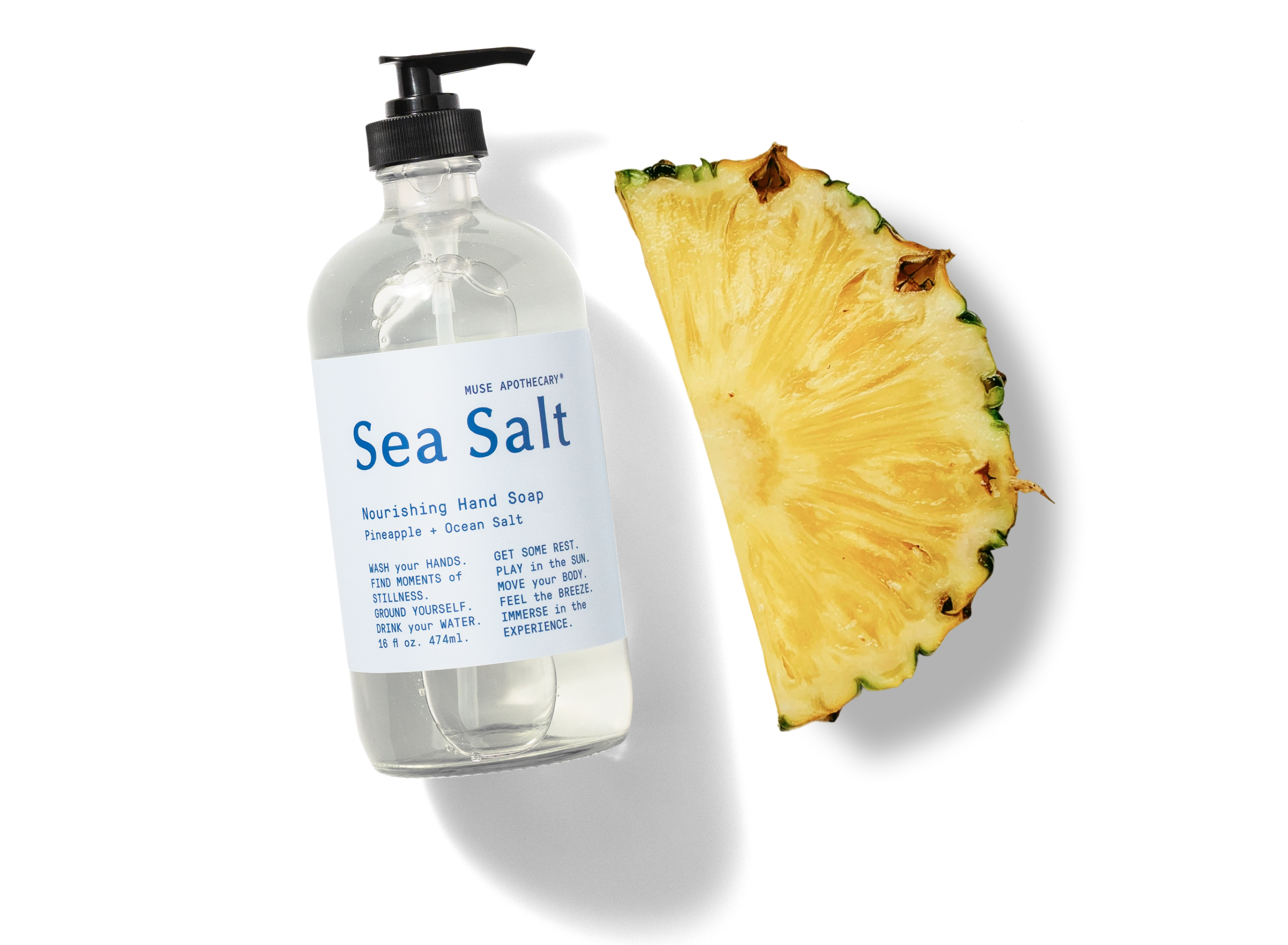 Sea Salt hand soap bottle with a slice of pineapple on a white background