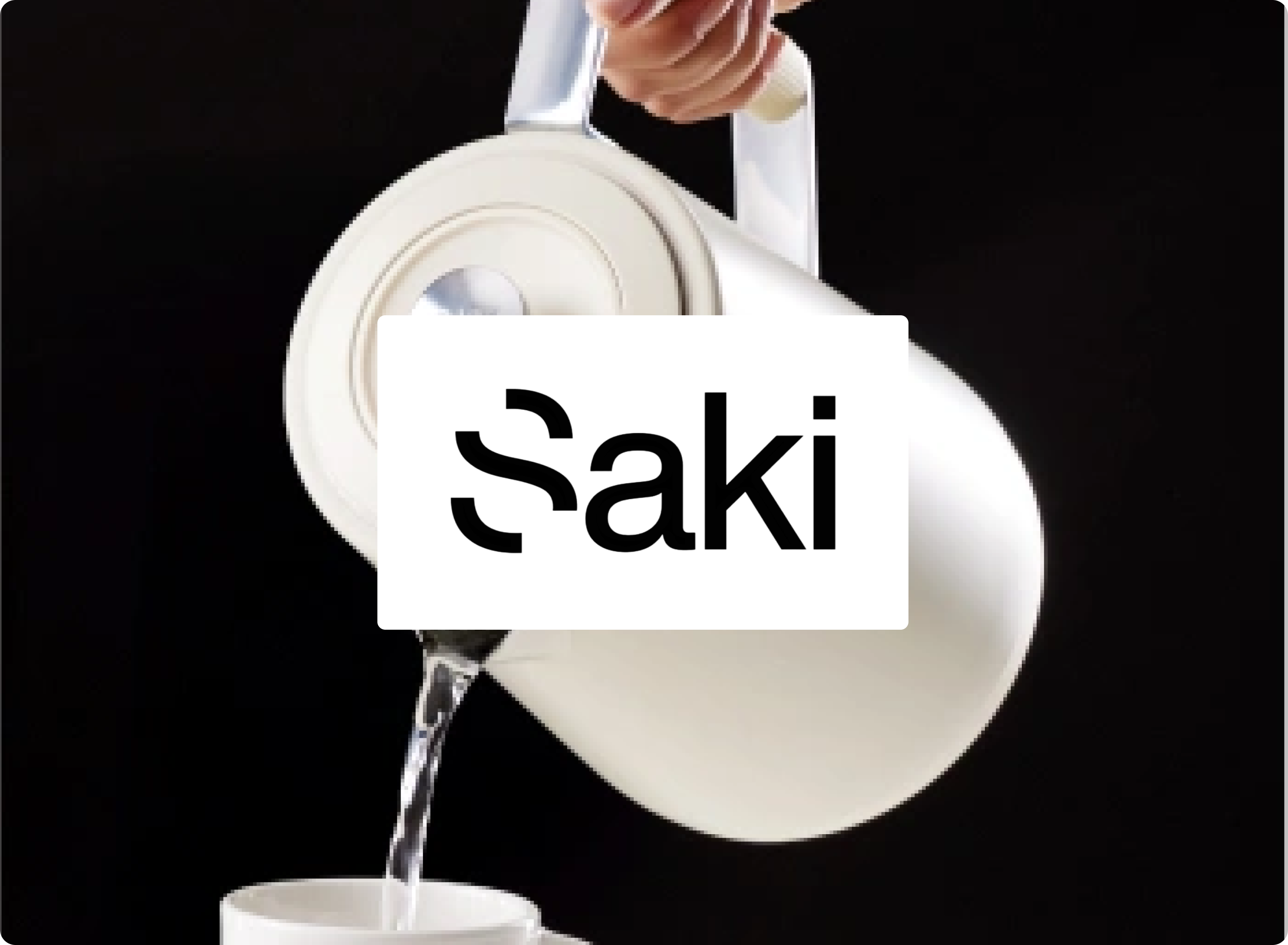 Person pouring water from a Saki product into a cup on a black background