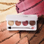 The RMS Beauty ReDimension Hydra Eyes Quartet, a talc-free palette featuring five shimmery shades and a dual-ended brush, is displayed on a textured background that reflects the eyeshadow colors.