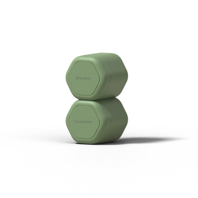 Two green, hexagonal Hair Duo Travel Containers by Cadence are stacked against a white background. The TSA-compliant top container is labeled Shampoo, while the reusable bottom one is labeled Conditioner.