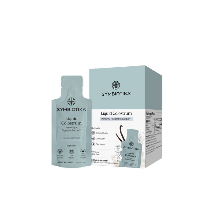 A pouch and box of Cymbiotika Liquid Colostrum Packets - Immunity + Digestive Support in Vanilla Sea Salt flavor are shown on a white background.