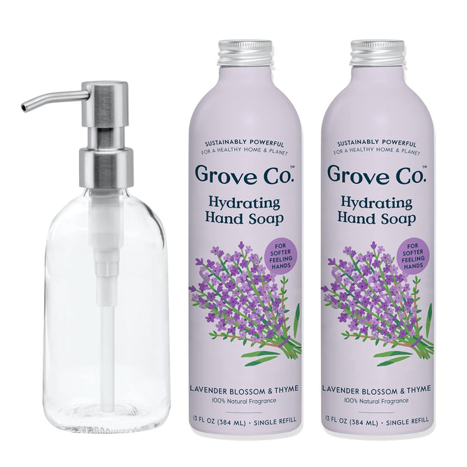 The Grove Co. Hand Soap Starter Pack Bundle includes two Hydrating Hand Soap Refills in Lavender Blossom & Thyme and a clear dispenser with a silver pump. The soap bottles feature lavender illustrations on a pale purple background.