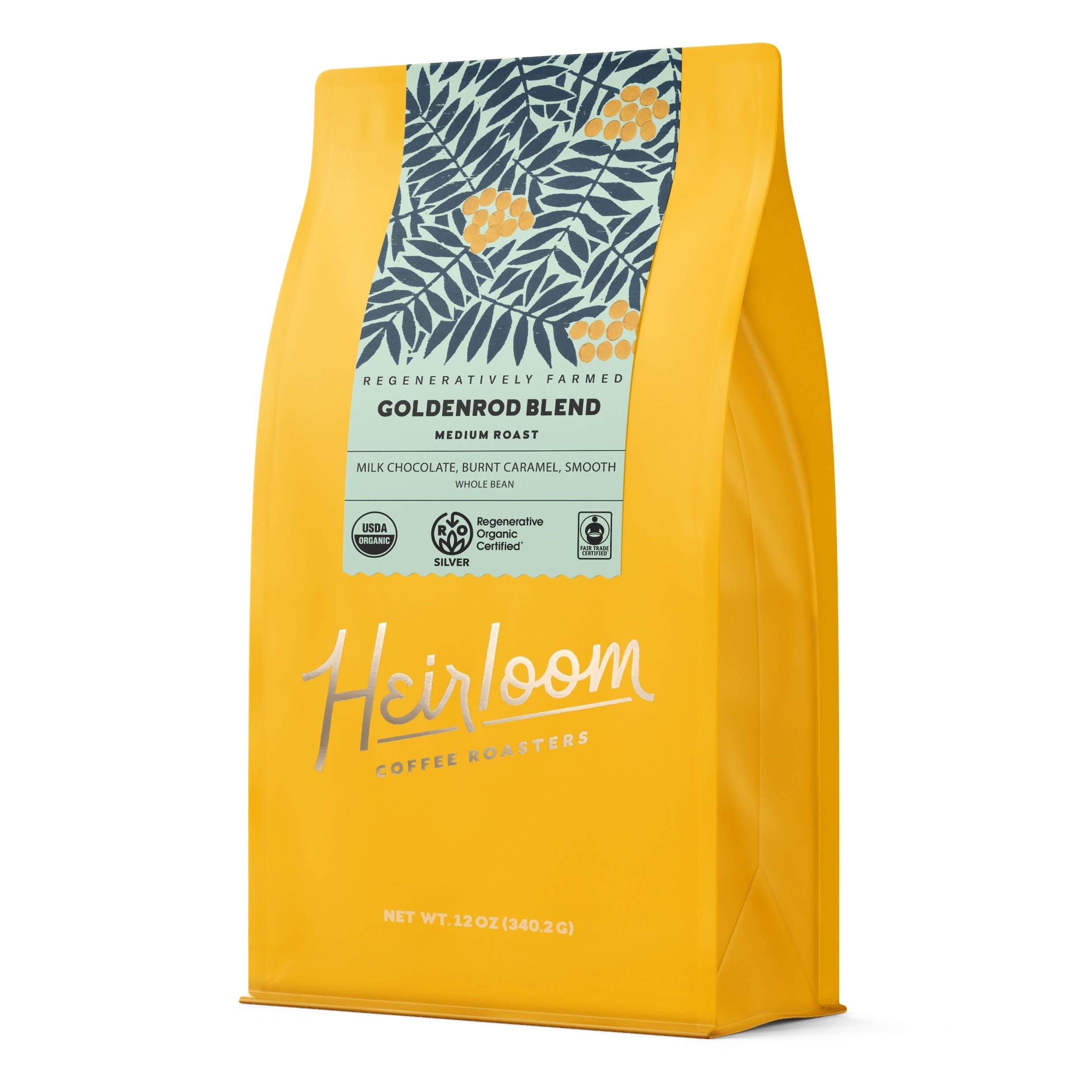 A yellow bag of Heirloom Coffee Roasters Goldenrod Blend ROC Whole Bean Coffee features a leafy floral design, Medium Roast label, Regenerative Organic Certified farming, and tasting notes of milk chocolate and burnt caramel.