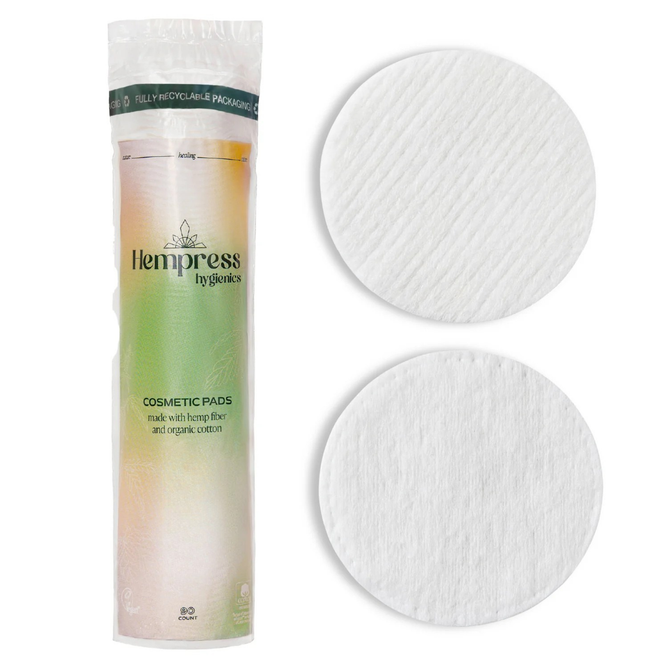 A package of Hempress Hygienics Hemp Cosmetic Rounds is displayed beside two round cotton pads—one textured, one smooth. The white packaging features a green and peach gradient label.