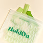 A translucent HoldOn Bags Compostable Sandwich Bag—BPA free and freezer safe—filled with celery stalks, tops peeking out, rests on a light beige background.
