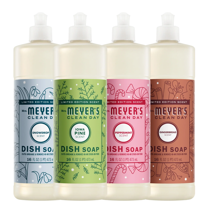 Four bottles of Mrs. Meyer’s Holiday Dish Soap Collection in light blue, green, pink, and brown, each featuring a seasonal scent label and festive illustrations.