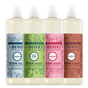 Four bottles of Mrs. Meyer’s Holiday Dish Soap Collection in light blue, green, pink, and brown, each featuring a seasonal scent label and festive illustrations.