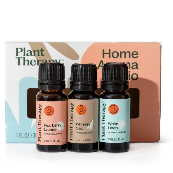 Three essential oil bottles, Pearberry Lychee, Whiskey Oak, and White Linen, rest elegantly in front of a pastel Plant Therapy Chasing Sunshine Essential Oil Blend Set box, offering an uplifting and grounding fragrance experience.