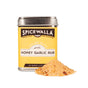 A yellow Spicewalla tin from the Garlic Lovers 3 Pack Collecountion sits beside a mound of seasoning—ideal for adding bold garlic flavor to your favorite savory meals—on a white background.