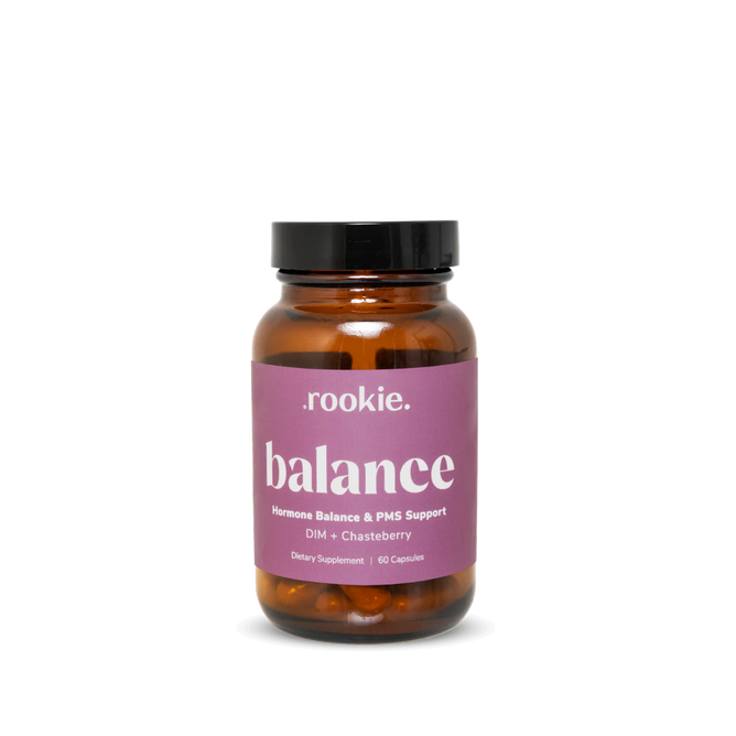 A brown glass bottle with a black lid, labeled "Rookie Wellness Balance Capsules - Hormone Balance + PMS Support." The purple label with white text highlights DIM and Chasteberry for estrogen detox. Contains 60 capsules.