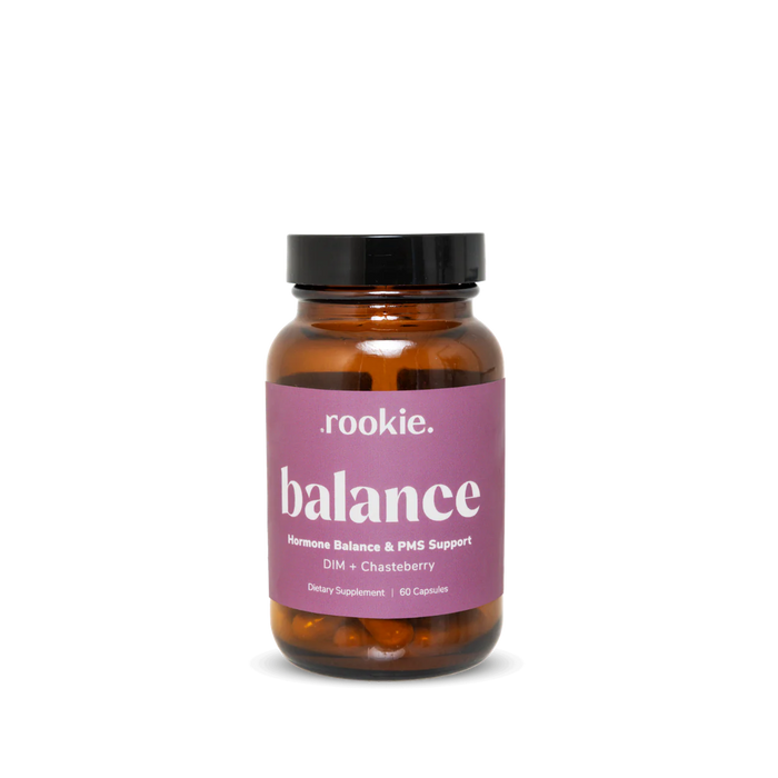 A brown glass bottle with a black lid, labeled "Rookie Wellness Balance Capsules - Hormone Balance + PMS Support." The purple label with white text highlights DIM and Chasteberry for estrogen detox. Contains 60 capsules.