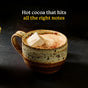 A rustic ceramic mug brimming with Diaspora Spice Co. Hot Cocoa Drink Mix, crowned by a generous marshmallow. The text above proclaims, Hot cocoa that hits all the right notes. Infused with single-origin spices and a touch of Madhur Jaggery, this comforting beverage stands out against a dark, minimalist background.