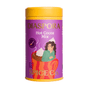 A purple and yellow tin labeled Hot Cocoa Drink Mix from Diaspora Spice Co. features an illustration of a woman in a green sweater sitting in a red mug topped with whipped cream, capturing the warmth of a hot cocoa blend crafted with single-origin spices and sweetened with Madhur Jaggery.