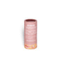 A cylindrical pink tube of Humble Brands Lip Balm - Paperboard stands upright on a white background, featuring white text and an illustration of stylized mountains in orange and yellow at the bottom.