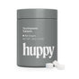 A gray huppy tin labeled “Toothpaste Tablets with Tin, 62 count, Net Wt. 36 g / 1.3 oz” holds sustainable toothpaste tablets. Three white cavity-fighting tablets are placed next to the container.