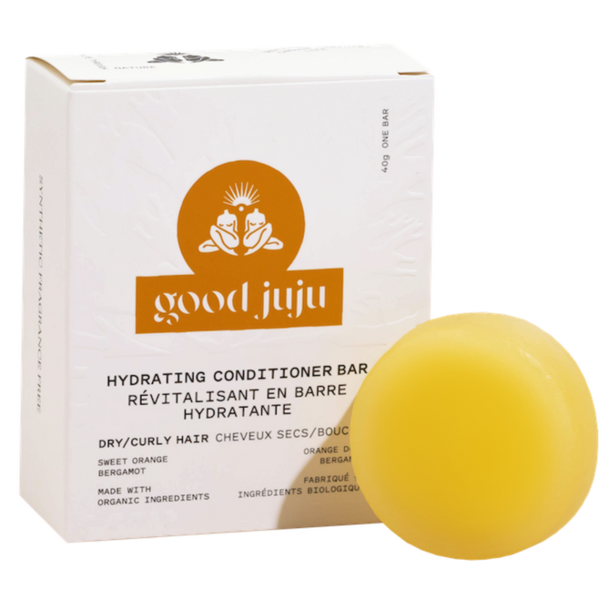 A yellow Hydrating Conditioner Bar by Good Juju Body & Home is displayed before a white box for dry/curly hair, featuring frizz control and organic ingredients with sweet orange and bergamot.