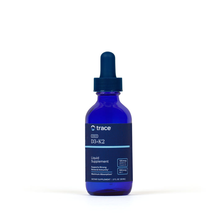 A blue glass dropper bottle labeled Ionic D3 + K2 Drops by Trace Minerals, with a dark blue dropper cap and featuring bioavailable vitamins D3 and K2, is photographed against a plain white background.