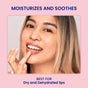A woman with long blonde hair applies FaceTory’s Berry Jam Lip Mask, smiling. The text reads: “MOISTURIZES AND SOOTHES. BEST FOR Dry and Dehydrated lips.” A light pink background completes the scene.