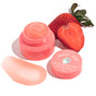 Open jar of FaceTory Berry Jam Lip Mask with strawberry label, product smear, and fresh sliced strawberry on a white background—your overnight lip treatment for soft, nourished lips.