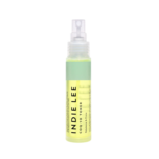 A clear spray bottle of Indie Lee CoQ10 Toner - Travel stands upright on a white background, featuring a green label and translucent cap. The hydrating toner, with light yellow liquid inside, is ideal for clean skincare routines.