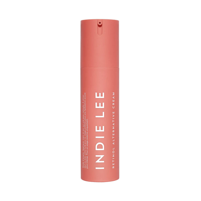 A pink cylindrical bottle with a pump dispenser labeled Indie Lee, containing Retinol Alternative Cream, a clean skincare anti-aging product.