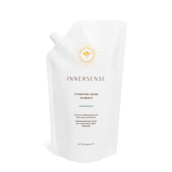 A white refill pouch of Hydrating Cream Hairbath by Innersense Organic Beauty, a silicone-free, hydrating shampoo with organic ingredients. Features a golden sunburst logo, minimal text, and a spout at the top left corner.
