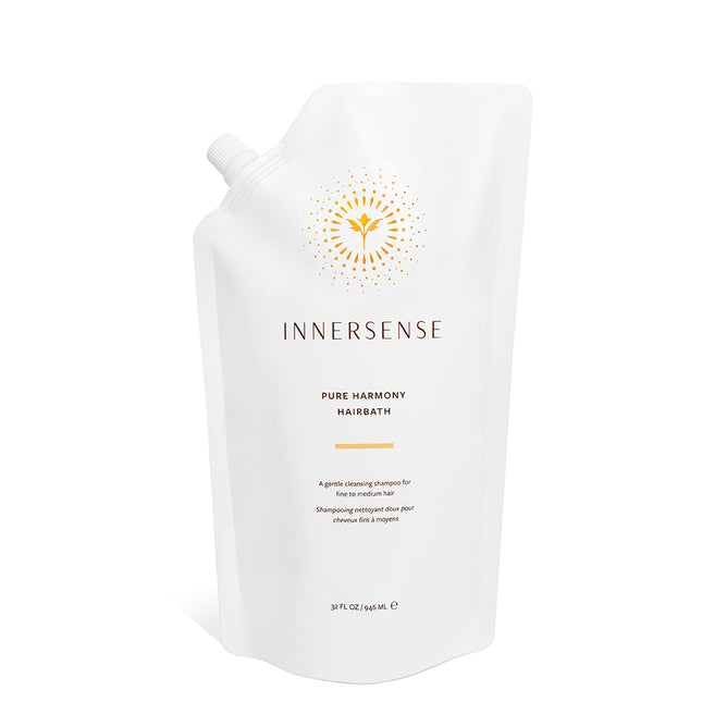 A white refill pouch of Innersense Organic Beauty Pure Harmony Hairbath, a sulfate-free shampoo, features a side spout, gold sunburst design, and upright stance against a white background.