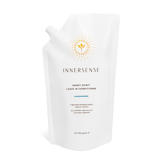A white refill pouch of Innersense Organic Beauty Sweet Spirit Leave In Conditioner, featuring a gold sunburst logo and minimalist text, delivers nourishing care with certified organic plant extracts and emollient oils.