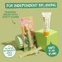 The Jack N Jill Silicone Toothbrush STAGE 2 and banana-flavored toothpaste for kids are shown on green props, with text: For independent brushing, Trusted by parents since 1949, and Safe. Fun. Yum!.