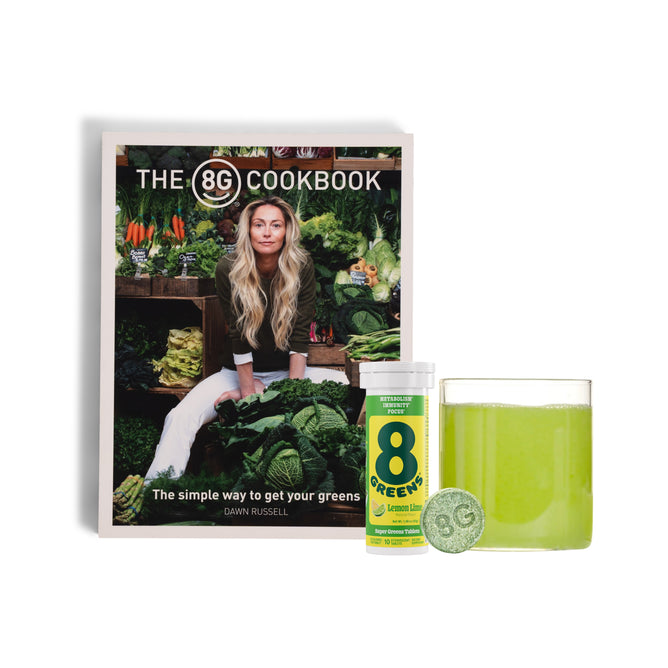 A free The 8Greens Cookbook, featuring a cover of a woman with leafy greens, stands behind 8Greens Super Greens Tablets and a green drink—your daily greens routine from 8Greens when you buy Super Greens Tablet.