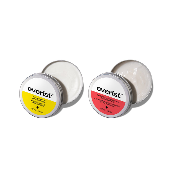 Two open metal tins of Everist's The Haircare Concentrate Tin Duo: Shampoo + Deep Conditioner are shown on a white background, one with a yellow label and the other pink, both revealing creamy white product inside.
