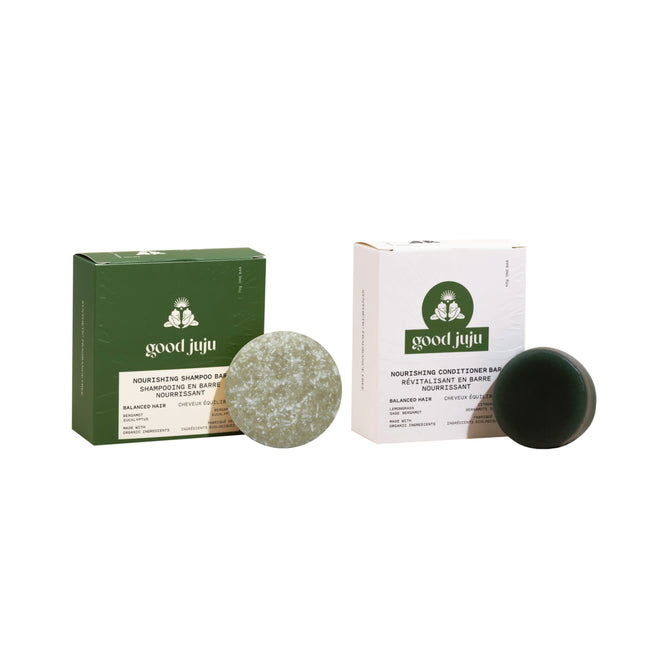 The Good Juju Body & Home Normal/Balanced Haircare Set features a green box with a round Shampoo Bar and a white box with a round Conditioner Bar, both upright on a white background.