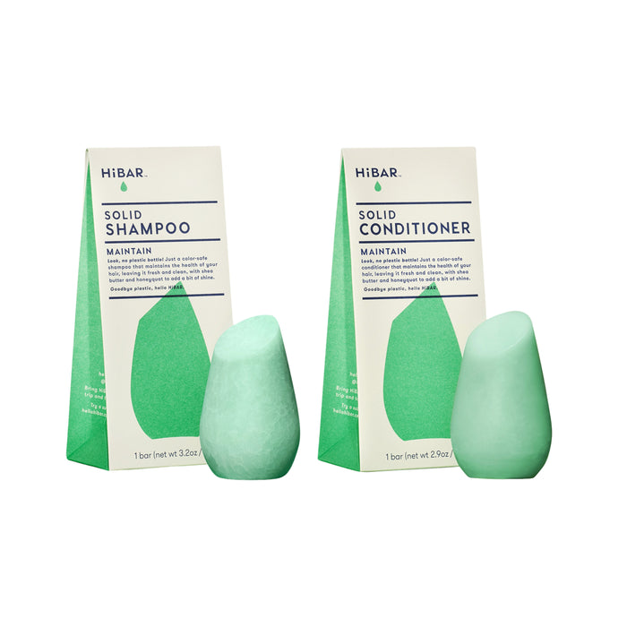 Two green HiBAR Maintain Haircare Set bars—shampoo and conditioner—stand side by side before matching green and white packaging, displaying their signature teardrop shape and eco-friendly design.