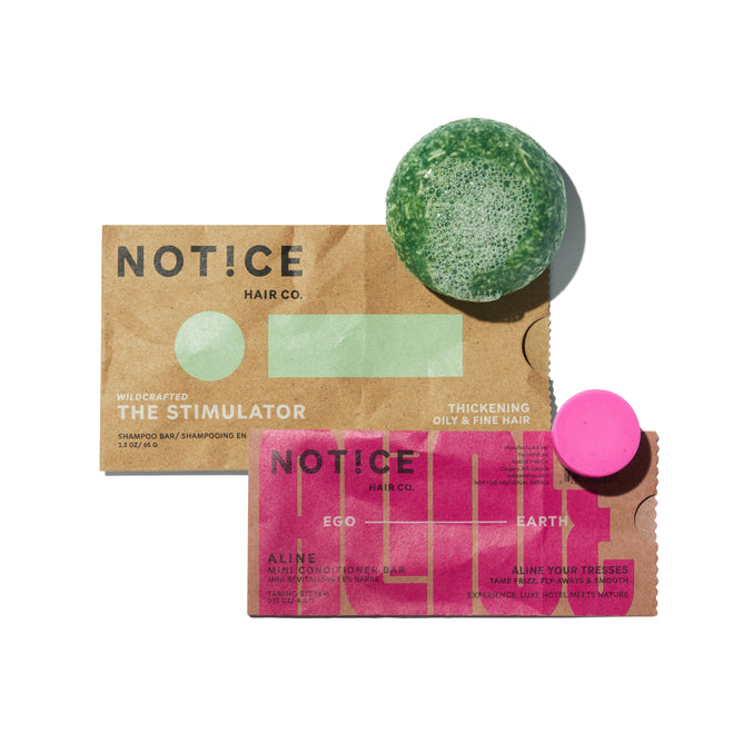 Two shampoo bars—one green and one pink—rest on packaging labeled NOTICE Hair Co, featuring the offer: Buy The Stimulator Shampoo Bar, Get ALINE Mini Conditioner Bar FREE. The Stimulator Shampoo Bar delivers a scalp clarifying experience, while the ALINE Mini Conditioner Bar gently nourishes your hair to meet its specific needs.