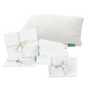 A fluffy white pillow with a green "Avocado" tag and neatly folded white sheets, bundled with ribbons and tags, are shown on a white background—Grove Collaborative’s Highest Impact Bedroom Swap Set: Everyday Sleep Essential.