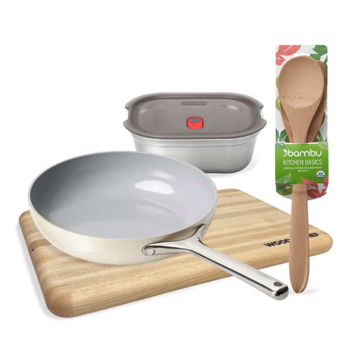 The Grove Collaborative Highest Impact Cooking Swap Set – Everyday Meal Prep Essentials, featuring a ceramic frying pan, wooden cutting board, stainless steel food container with lid, and packaged wooden spoon, is arranged on a white background.