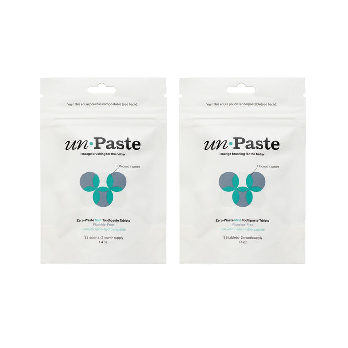 Two white Unpaste pouches labeled "Buy One, Get One Free - Fluoride-Free Mint Toothpaste Tablets," each plastic-free with green and blue circles, contain 125 eco-friendly tablets—enough for a two-month supply.