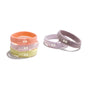 On the left, four pastel-hued KOOSHOO Organic Hair Ties—peach, yellow, light green, and lavender—are stacked. Two more lavender hair ties are on the right. Each eco-friendly tie features a patch with two white dots.