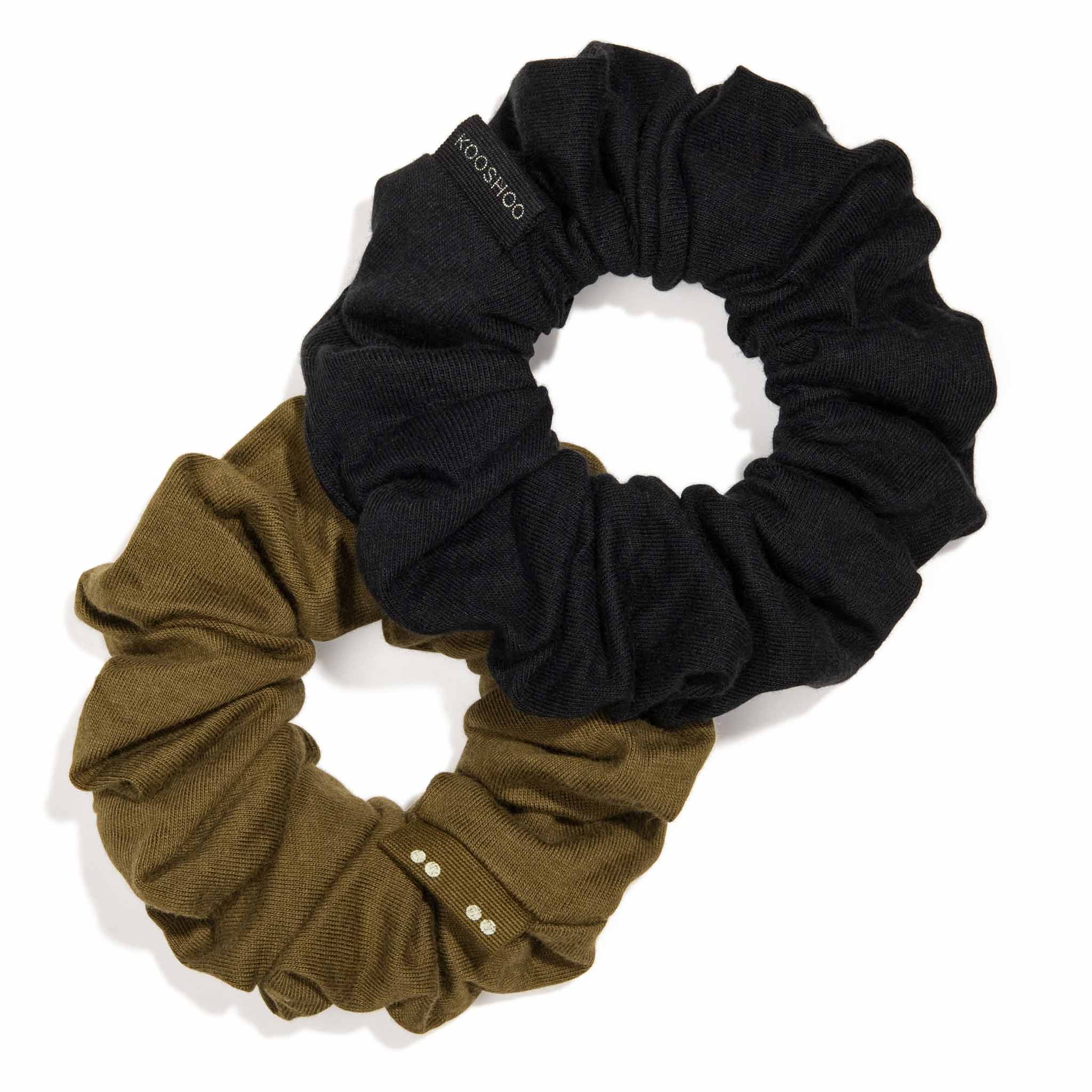 Two large KOOSHOO Scrunchies in organic cotton are displayed in an intertwined figure-eight: one is solid black with a branded label, the other olive green with small white dots.