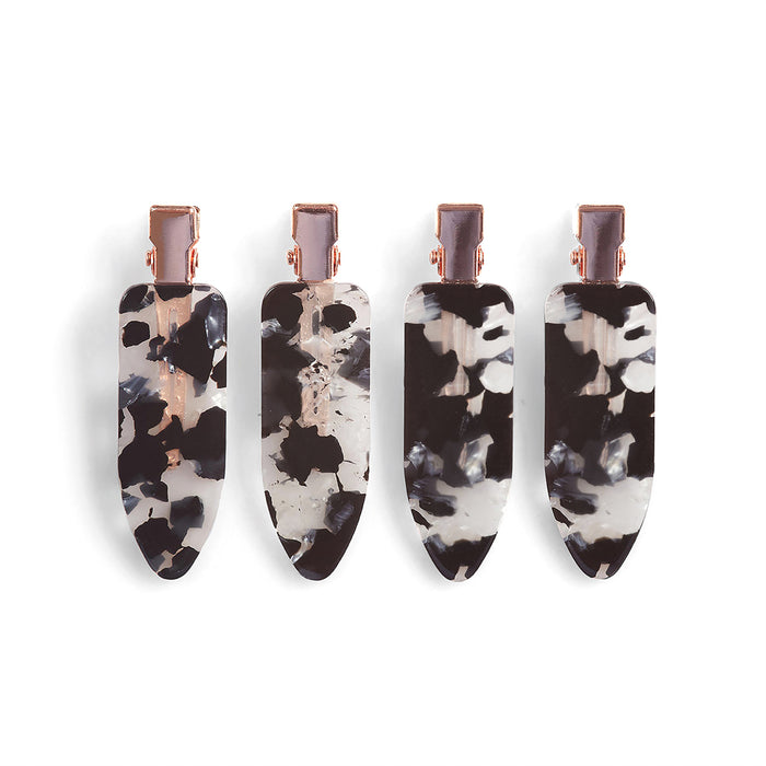 A set of four teardrop-shaped Eco-Friendly Creaseless Clips by Kitsch, featuring metal clasps and a tortoiseshell pattern with black, white, and gray swirls, elegantly holds hair without harming the environment, using materials sourced responsibly.