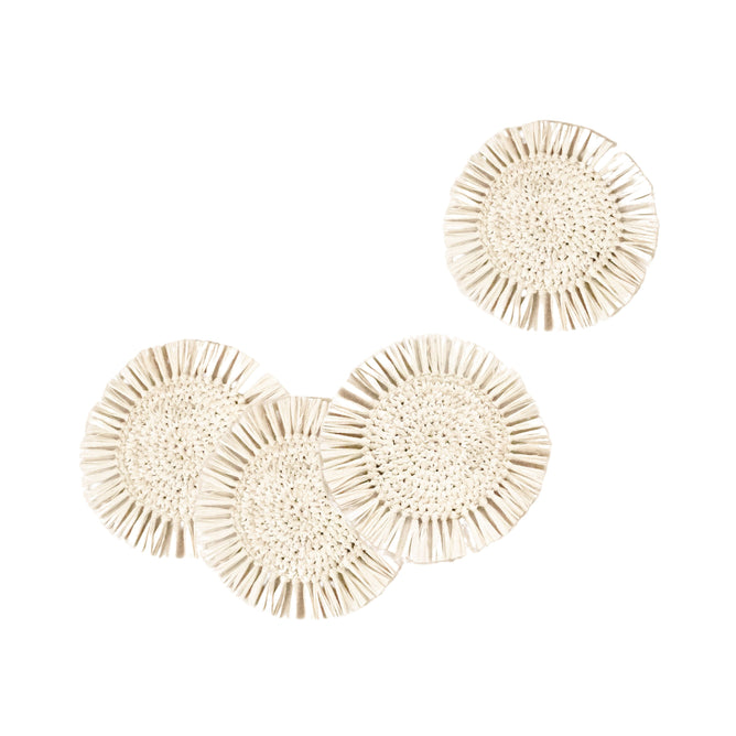 The LIKHA Raffia Fringe Coasters, set of 4, are round and beige with fringed edges, displayed on a white background—three overlapping at the bottom left, one placed apart at the top right.