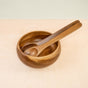 The Acacia Essential Serving Set by LIKHA features a wooden bowl with sustainably sourced spoon and fork, elegantly placed on a light wood surface.