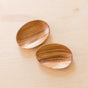 A set of two LIKHA Acacia Oval Plates (7), crafted from sustainably sourced wood with a visible natural grain, rest slightly overlapping on a light wooden surface.