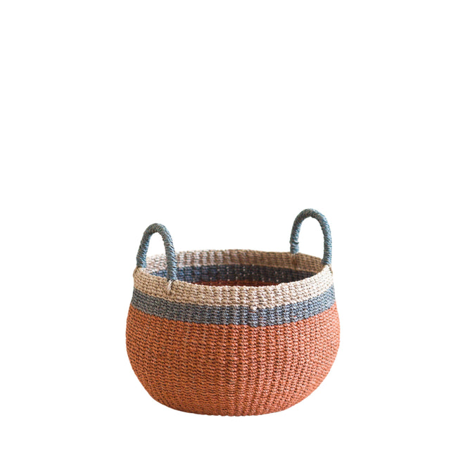 The LIKHA Abaca Bulge Basket is a round, handwoven Manila hemp basket with two handles, featuring a wide orange base, blue middle stripe, and natural tan top—displayed on a white background.
