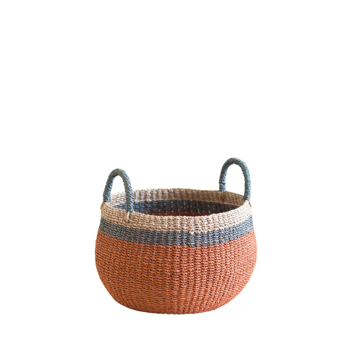 The LIKHA Abaca Bulge Basket is a round, handwoven Manila hemp basket with two handles, featuring a wide orange base, blue middle stripe, and natural tan top—displayed on a white background.