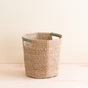 The LIKHA Abaca Octagon Basket, crafted from natural abaca fiber with green-wrapped handles, sits on a light wooden surface against a neutral background.