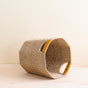 The LIKHA Abaca Octagon Basket, crafted from ethical abaca fiber, features two handles wrapped in natural mustard yellow thread, adding a subtle accent to its neutral design.