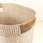 A close-up of LIKHAs Abaca Rounded Oval Basket, set of 2—artisan-crafted from natural fibers with reinforced rectangular handles—offers sustainable storage on any light-colored surface.