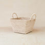 The LIKHA Abaca Tapered Square Tabletop Basket with Handles is a handwoven abaca fiber basket, featuring two round handles. Filipino artisans craft each piece, shown here on a light wooden surface against a neutral background.