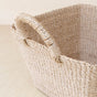 A close-up of the LIKHA Abaca Tapered Square Tabletop Basket with Handles, handwoven by Filipino artisans from natural abaca fiber, displayed on a light wooden surface.